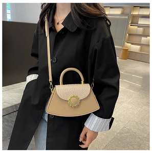 Model trägt eine beige Umhängetasche mit Krokodilprägung und goldenem Sonnenblumenverschluss