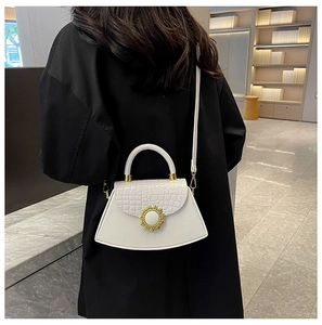 Modische weiße Tasche mit Krokostruktur und goldener Sonnenschnalle über der Schulter getragen