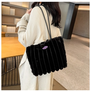 Detail view of black faux fur tote bag with vertical stripes and long leather straps