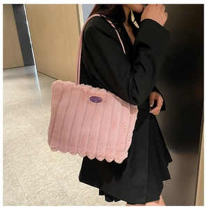Detail of pink plush tote bag with vertical stripes and fashion label on black blazer