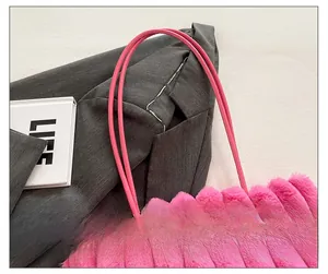 Detail of pink plush tote bag with vertical stripes and slim leather handles on grey suit