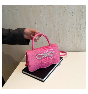 Macro shot of pink crocodile texture with a sparkling rhinestone bow on a stylish handbag