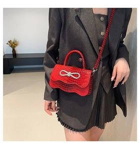 Close-up of red crocodile pattern handbag with sparkling diamond bow buckle detail