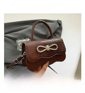 Detail of brown crocodile pattern handbag with sparkling silver rhinestone bow decoration