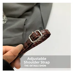 Detail of adjustable crocodile pattern strap with silver square metal buckle