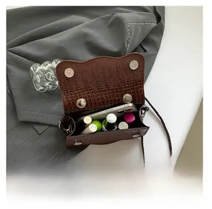 Detail view of the brown crocodile texture bag showing interior capacity with lipsticks and phone