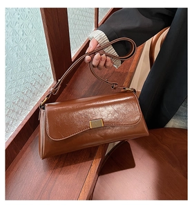 Close-up of brown vintage leather baguette bag with a glossy finish and gold metal buckle