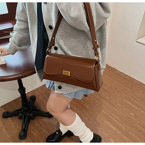 Borsa baguette vintage marrone con fibbia dorata su un tavolo di legno nel caffè