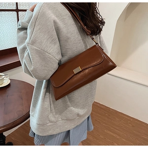 Detail of vintage brown shoulder bag with sleek gold-tone hardware and retro flap design