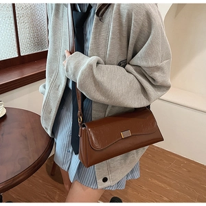 Close-up of a vintage brown leather baguette bag featuring a sleek metal buckle closure
