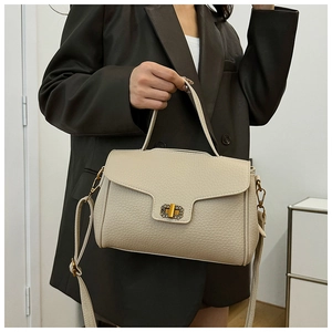 Gros plan du sac à main beige en cuir texturé avec fermoir rotatif doré élégant