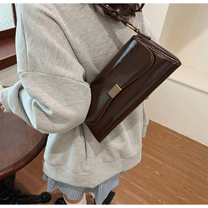 Dettaglio della borsa baguette marrone lucido con fibbia in metallo dorato testurizzato