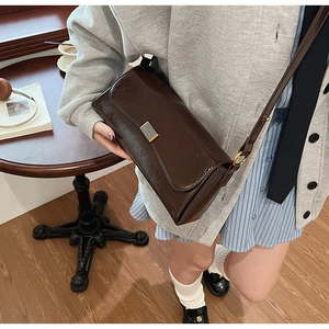 Dettaglio della borsa baguette vintage marrone con fibbia dorata sulla spalla