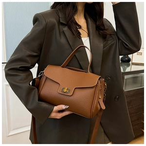 Détails du sac en cuir grainé caramel avec fermoir doré porté par un mannequin
