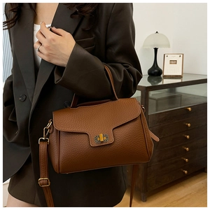Sac à main en cuir litchi marron avec fermoir doré présenté dans un décor de style