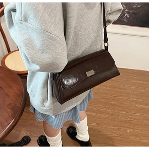 Dettaglio della borsa a spalla in pelle verniciata marrone con fibbia in metallo dorato