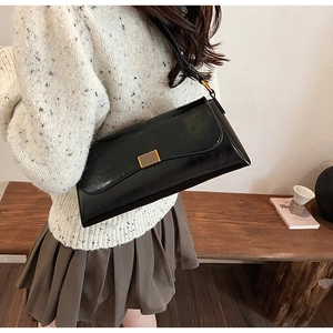 Dettaglio borsa baguette vintage nera lucida con elegante chiusura in metallo dorato