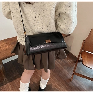 Dettaglio di una borsa baguette vintage nera con finitura lucida e chiusura in bronzo