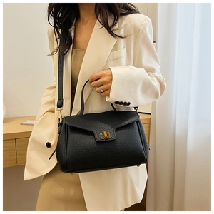 Détail d'un sac à main noir en cuir grainé avec fermoir doré et bandoulière amovible