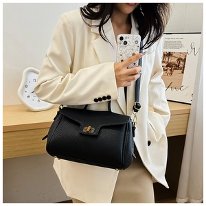 Détail du sac à main en cuir grainé noir avec fermoir doré sur un mannequin en costume