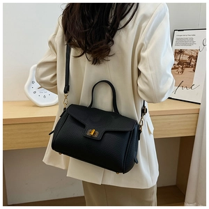 Vue arrière d'un mannequin portant un sac à main en cuir noir avec fermoir doré et costume blanc