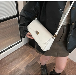 Detail of a white minimalist crossbody bag featuring a sleek metal rectangular lock clasp