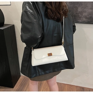 Close-up of white leather baguette bag with premium gold metal buckle detail on shoulder