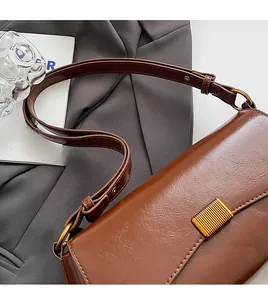 Macro view of vintage brown leather baguette bag with golden metal buckle and wide strap