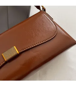 Detail of brown oil-wax leather shoulder bag with textured finish and gold metal buckle