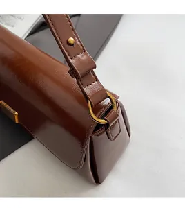 Detail view of dark brown oil leather handbag with adjustable strap and gold hardware