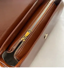 Detail view of smooth golden zipper and magnetic buckle on vintage brown leather bag
