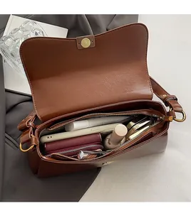 Close-up of brown leather flap bag interior showing capacity for daily essentials