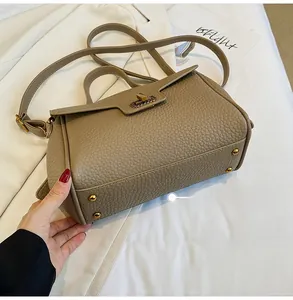 Détails de la texture cuir taupe et des picots de protection dorés au bas du sac à main