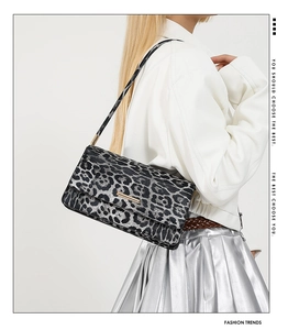 Detail of leopard print shoulder bag with gold clasp shown on a model