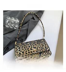 Detail view of leopard print baguette bag with gold metal buckle on grey blazer
