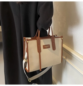 Detail of canvas tote bag with brown leather trim and fashion label on a model