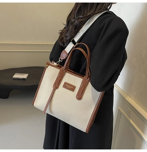 Detail of canvas and leather stitching on a large tote bag with a fashion shoulder strap