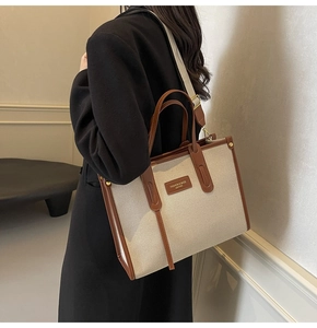 Detail of canvas tote bag with leather trim and adjustable strap on a shoulder