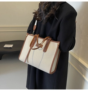 Detail view of canvas tote bag with brown leather trim and adjustable shoulder strap