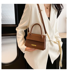 Detail of a brown lychee pattern leather square bag with FASHION lettering text