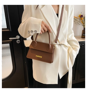 Close-up of brown litchi pattern leather bag with Fashion text and adjustable strap