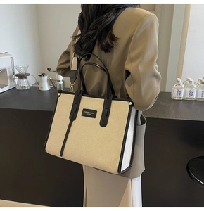 Model view of a large canvas tote bag with contrast leather trim and nylon shoulder strap