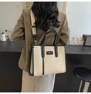 Detail of canvas tote bag with black leather trim and wide adjustable shoulder strap