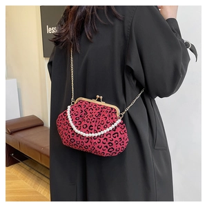 Detail of red leopard print shell bag with pearl handle and gold chain on model