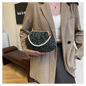 Detail of green leopard print shell bag featuring a pearl handle and gold chain strap