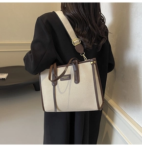Detail of canvas tote bag featuring brown leather trim and adjustable fabric shoulder strap