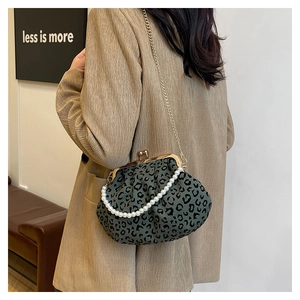 Detail of leopard print shell bag featuring pearl handle and gold chain on model