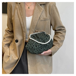 Detail of dark green leopard print shell bag with pearl handle and gold chain strap