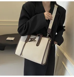 Close-up of canvas tote bag with brown leather trim and golden hardware detailing