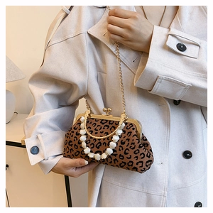 Detail of leopard print shell bag with golden metal clasp and pearl beaded handle